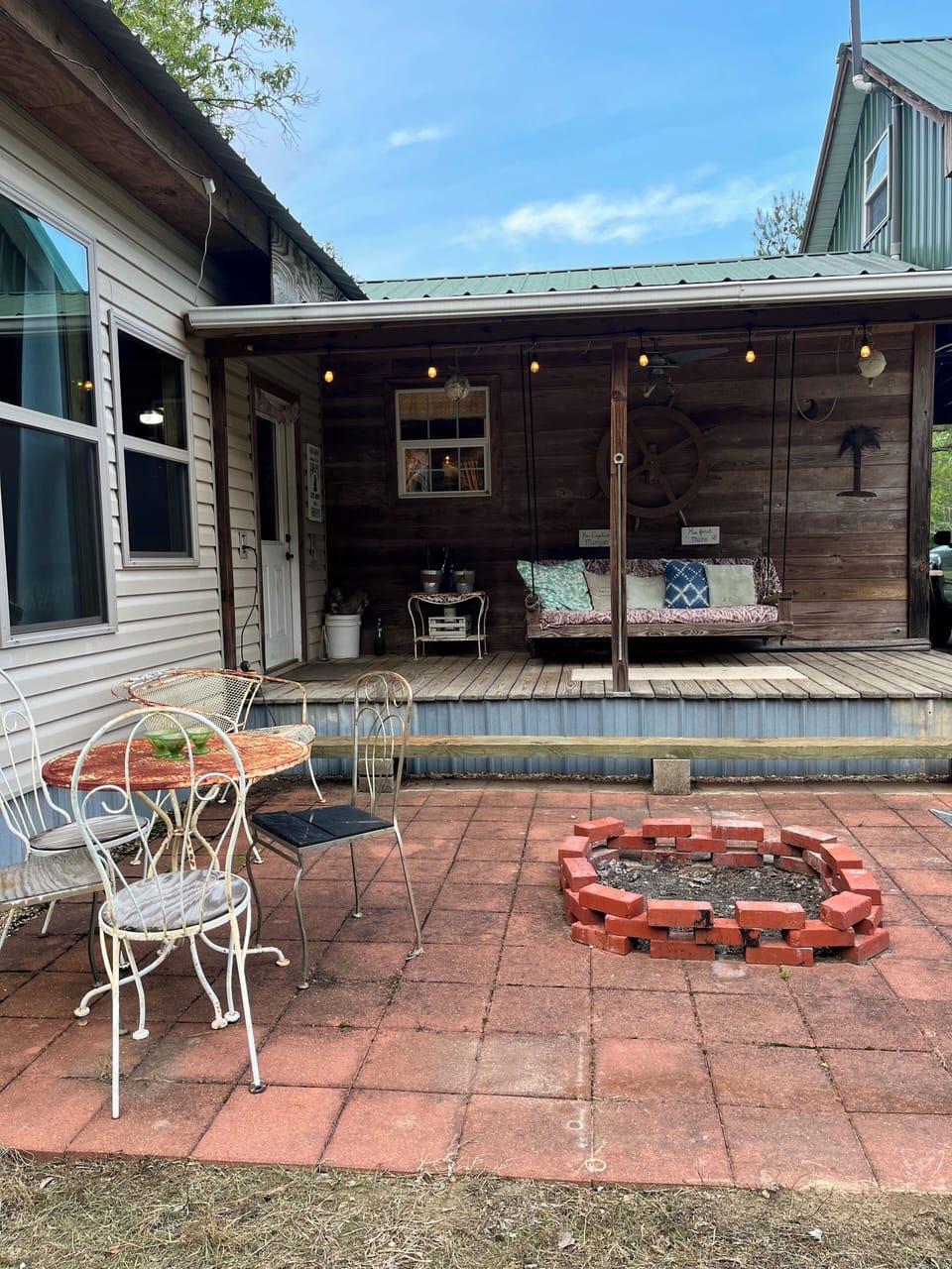 Back patio with porch swing/ daybed, lights, grill, and fire pit.