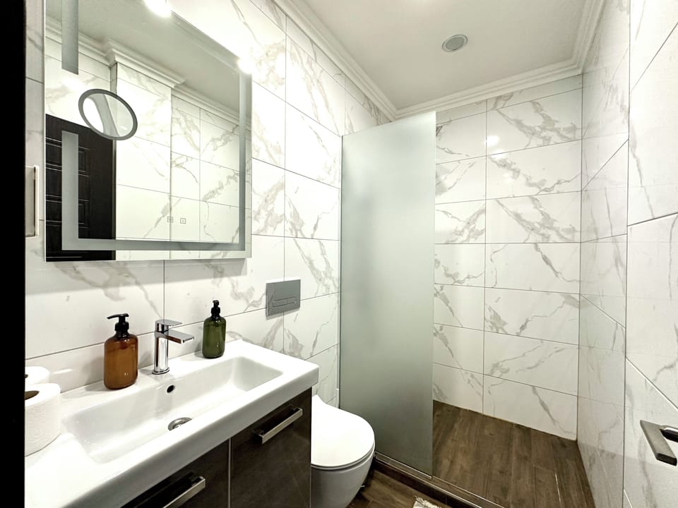 Modern bathroom with elegant marble tiles and a spacious rain shower. Refresh and relax in style during your stay!