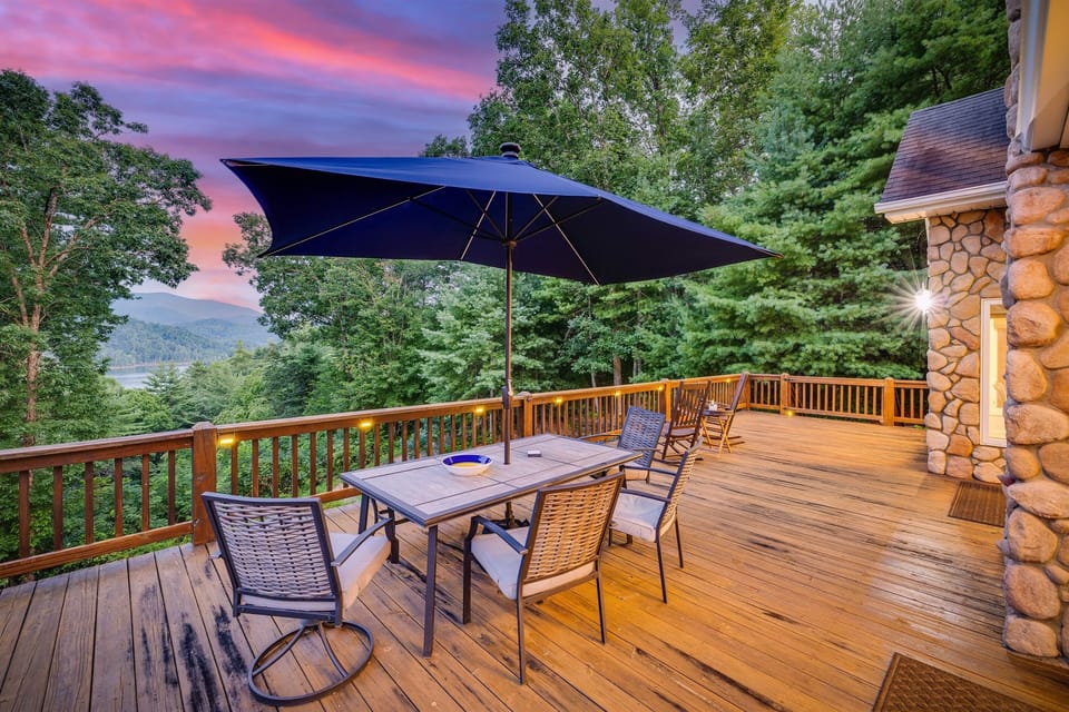 Main floor deck with large dining table, umbrella, rocking chairs, and grill.