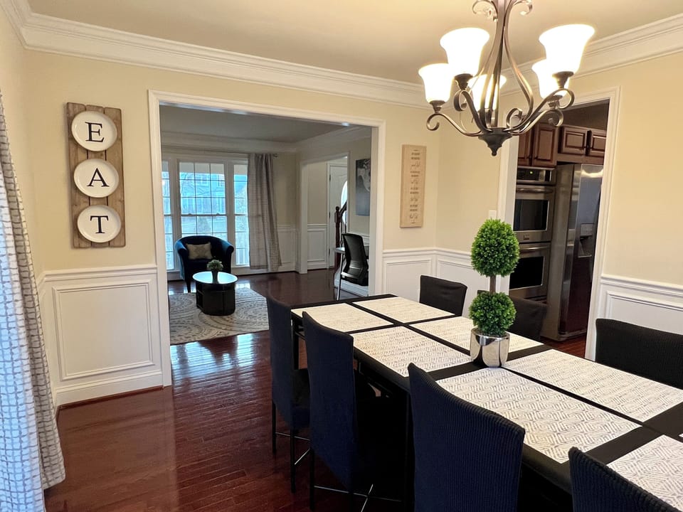 Dining room table seats 8 and is situated by large windows and backyard views.