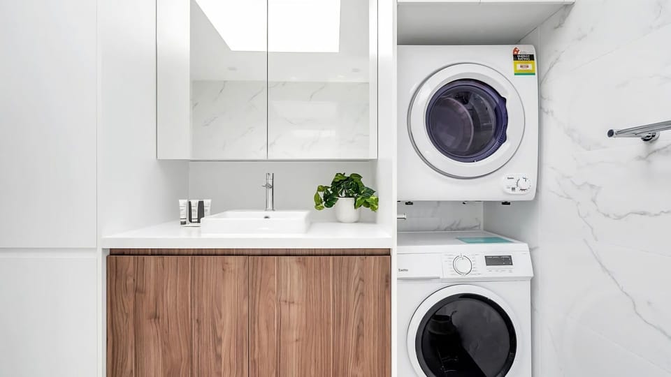Small space, big functionality. Love this sleek laundry-to-bathroom transition.