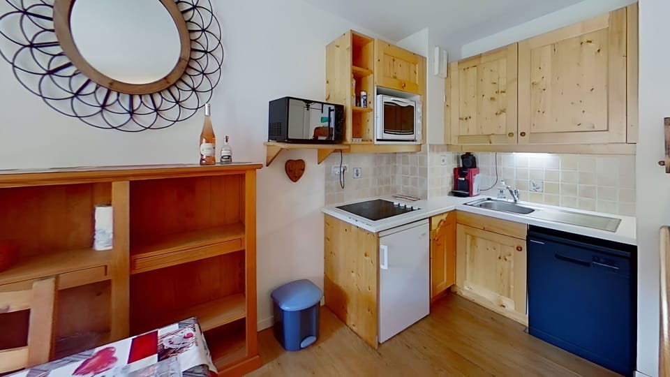 The fully equipped kitchen features a  four-burner stovetop, a microwave, a dishwasher, a fridge, and a Nespresso coffee machine, making it easy to prepare meals after a day on the slopes. The wooden cabinets and tile backsplash give the space a warm and 