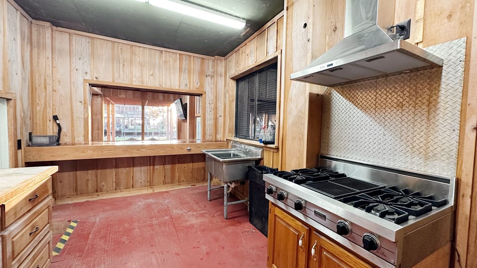 Rustic secondary kitchen with a commercial-style stove and stainless steel sink.