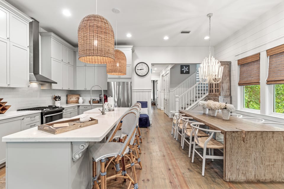 Your open-concept kitchen flows seamlessly into the dining area, where warm woven lighting and coastal textures create the perfect gathering space.