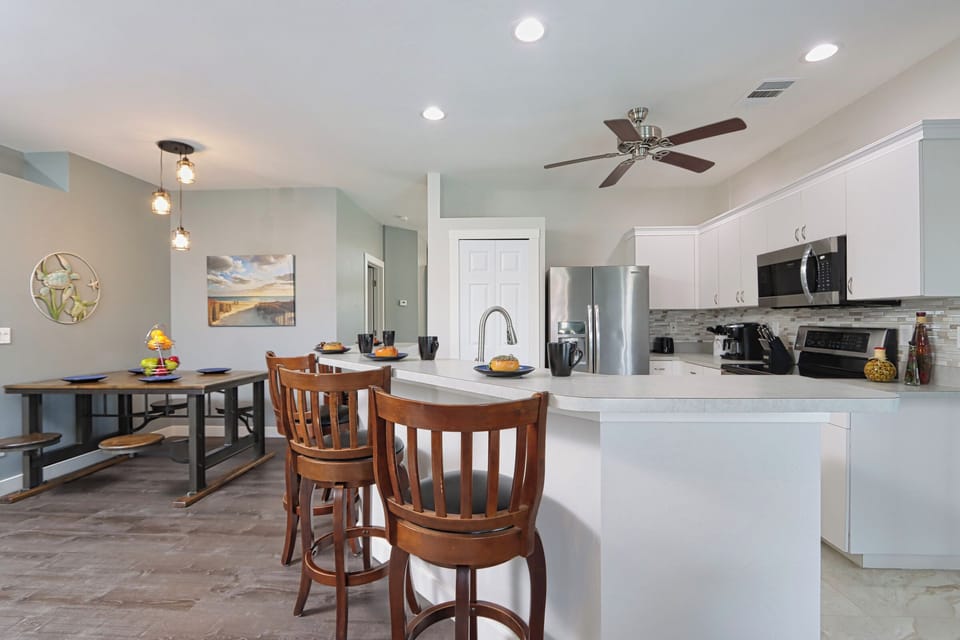 Kitchen with breakfast bar, stainless steel appliances, & dining table