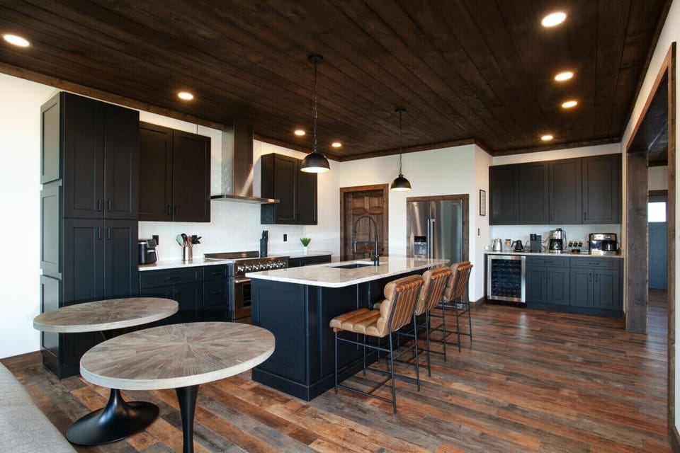 A kitchen that makes hosting effortless with its expansive island, sleek black cabinetry, and warm wood floors. Style and function in every detail.