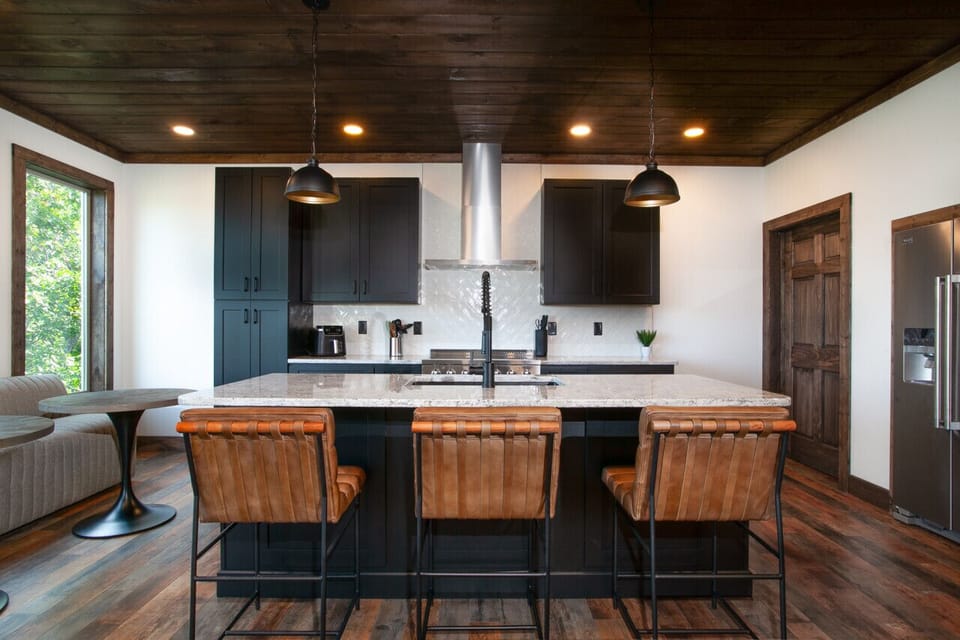 Prepare meals in style with this chef-inspired kitchen, featuring a stunning blend of dark cabinetry and clean white countertops.
