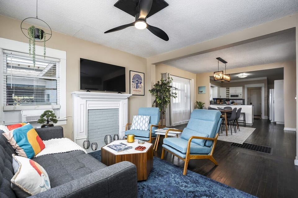 Living room space with comfortable seating, 58` smart TV, AC, ceiling, electric candles, and books