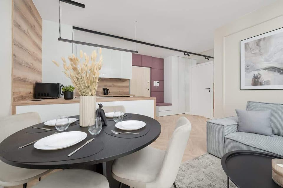 A stylish living-dining space with gray furnishings and a black round table. Perfect for meals and relaxing in comfort.