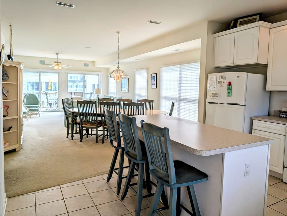 10 Dune Road (39544) - Kitchen & Island Seating - The fully equipped kitchen features a long breakfast bar with stool seating, providing additional space for casual dining or morning coffee while overlooking the main living area.