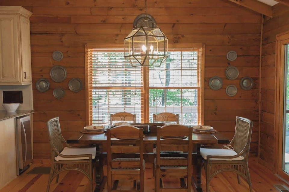 The dining area is well-lit by large windows that frame beautiful views of the surrounding nature.