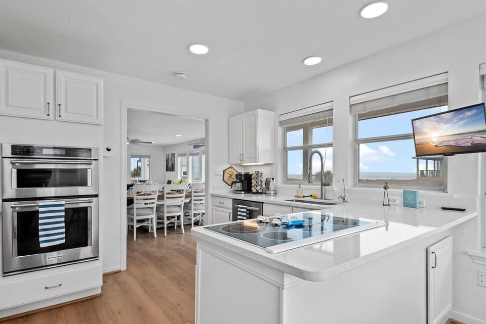 The gleaming white kitchen features sleek stainless steel appliances, combining elegance and functionality.
