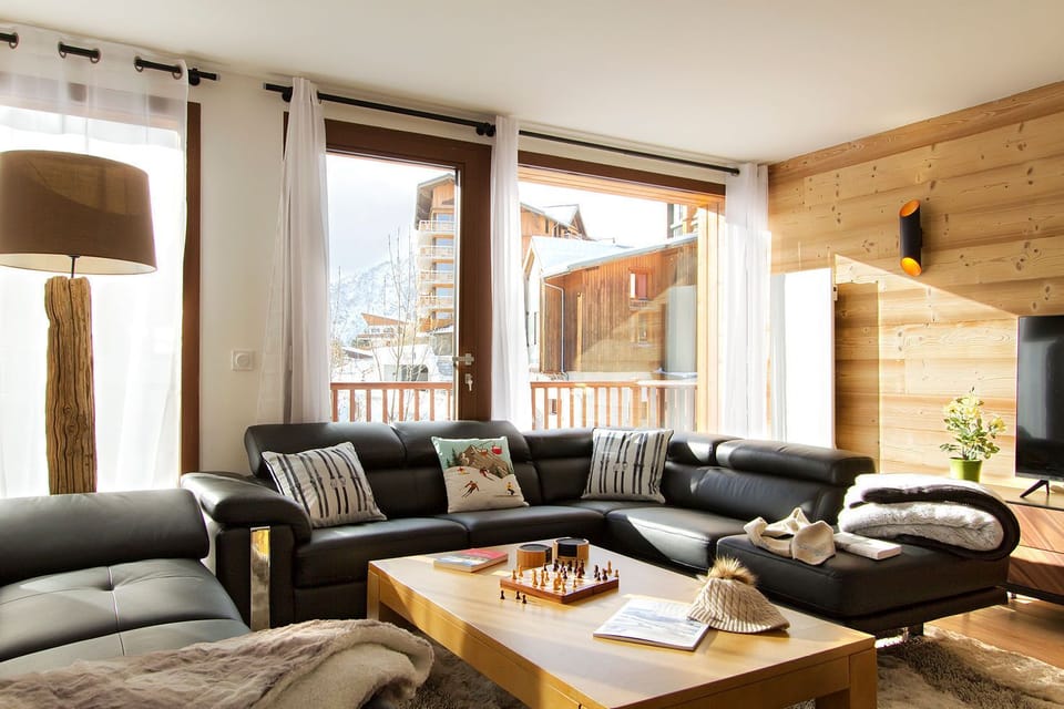 Relax in this spacious living room, featuring plush seating, warm wooden accents, and large windows that offer breathtaking mountain views. Perfect for unwinding after a day of adventure.