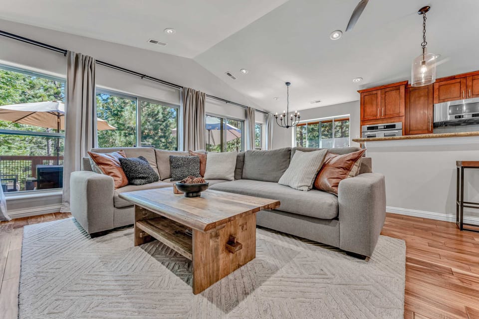 Living Room: L-shaped couch, 65” Smart TV, connected to kitchen/dining room, opens to patio