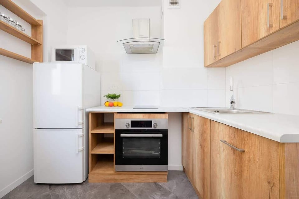 A compact kitchen with modern appliances and wooden cabinetry. The layout is functional and clean.