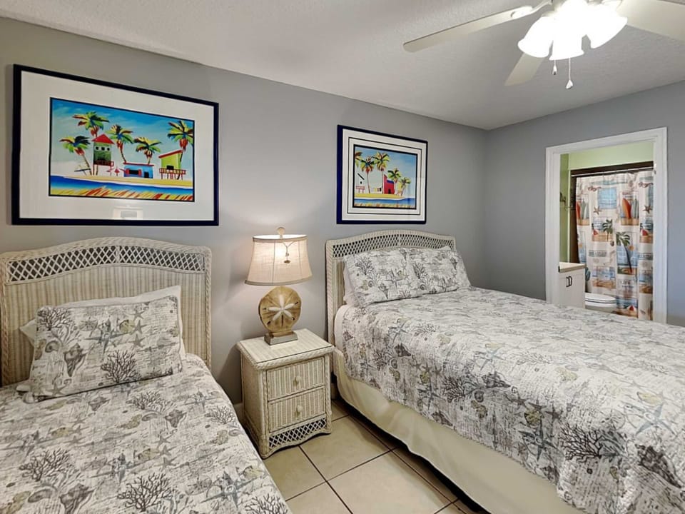 - Comfy setup for kids or extra guests with twin and full beds in a playful style
- Enjoy direct access to the second bathroom for added convenience and privacy
- Beach inspired art, wicker accents, and soft lighting complete the room