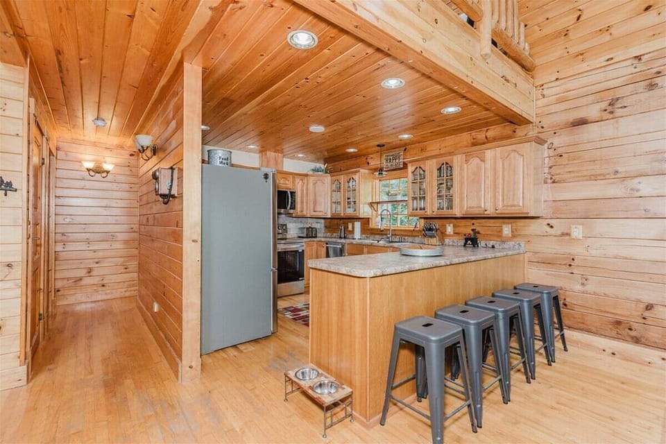 Full kitchen featuring stainless steel appliances, spacious counters, and a breakfast bar with stools for casual dining.