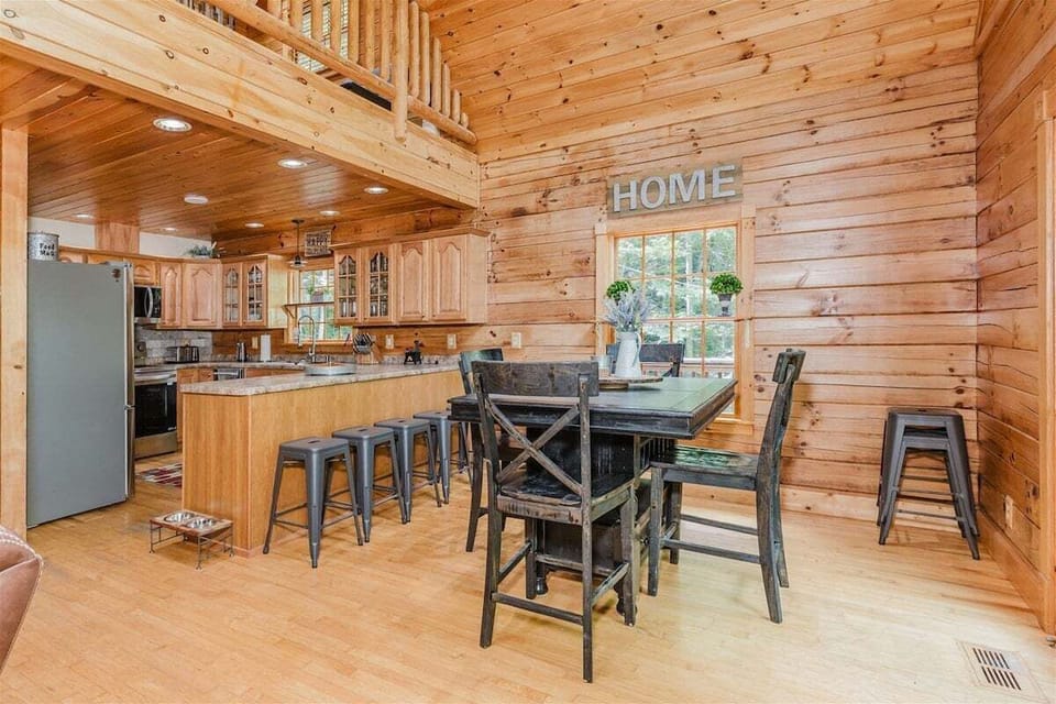 Dining table and full kitchen with bar seating, stainless appliances, and open floor plan for family meals.