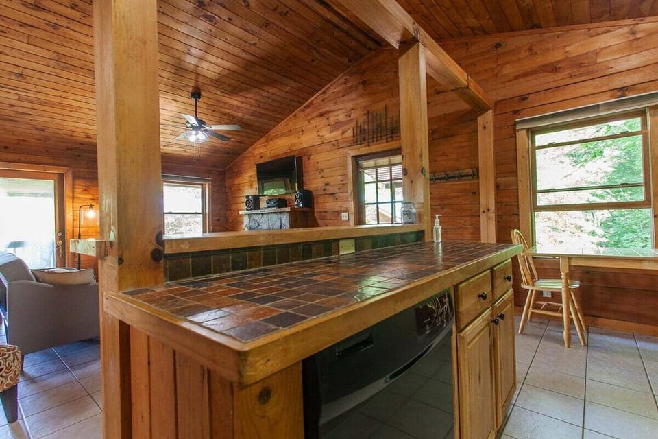 Open-concept interior showcasing the kitchen bar, living area, and exposed wood beams. The spacious layout creates a comfortable gathering area in the Smoky Mountains.