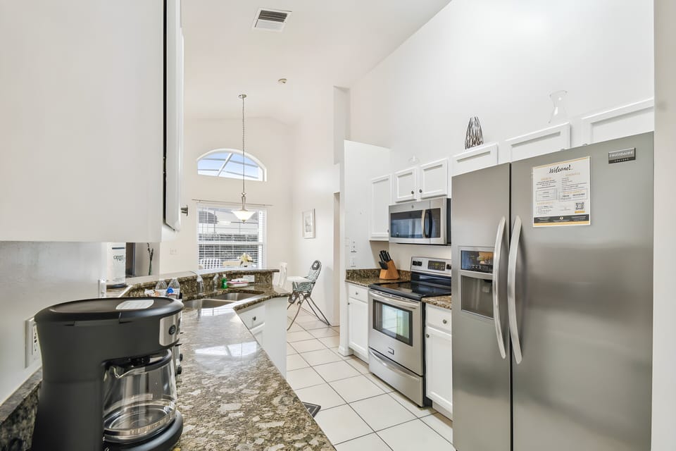 This bright and spacious kitchen features sleek stainless steel appliances and a beautiful granite countertop perfect for culinary adventures. High ceilings and abundant natural light create an inviting, warm atmosphere.