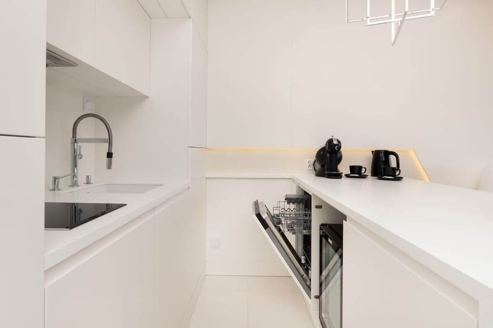 A white kitchen with built-in appliances and minimalist design. Perfect for lovers of sleek, modern interiors.