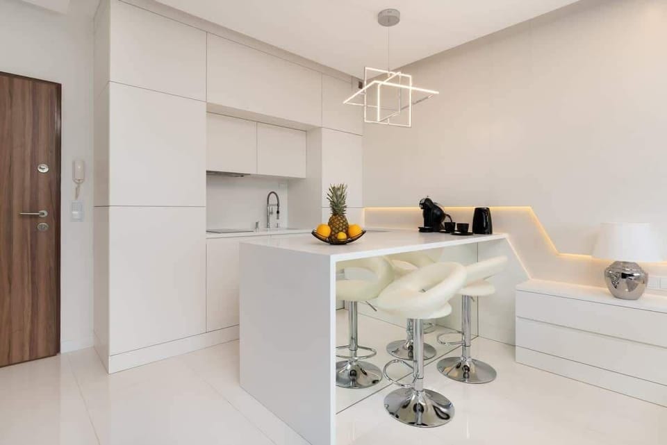 A clean, minimalistic space with white walls and built-in storage. A kitchen island adds functionality and elegance.