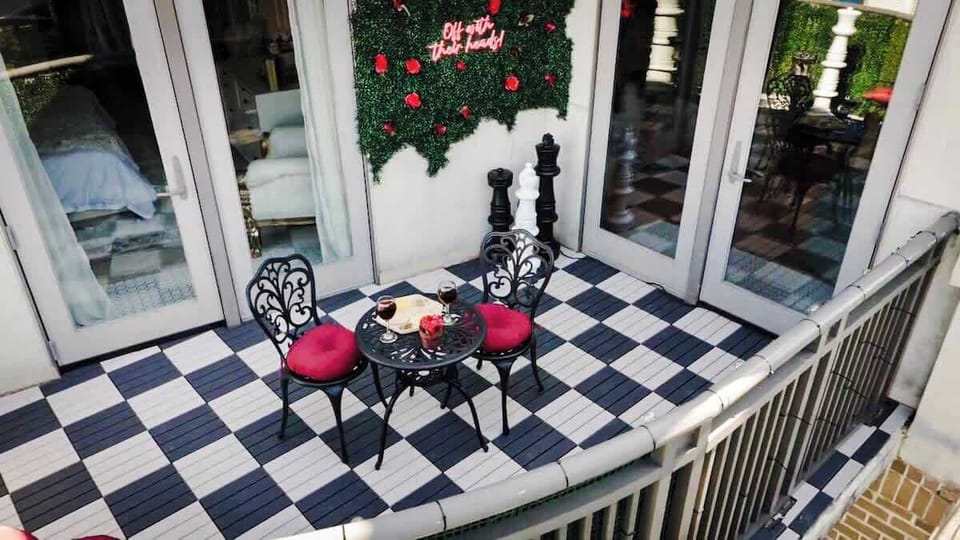Whimsical Uptown Charlotte balcony with bold checkerboard tile, café bistro seating, and playful design details—perfect for morning coffee, sunset wine, or relaxing during your mid-term stay.