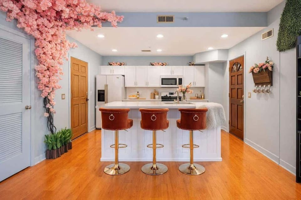 Bright, fully equipped kitchen with modern appliances, a generous island, and velvet bar seating. Cherry blossom accents add character, making it a welcoming space for cooking, gathering, and extended Uptown Charlotte stays.