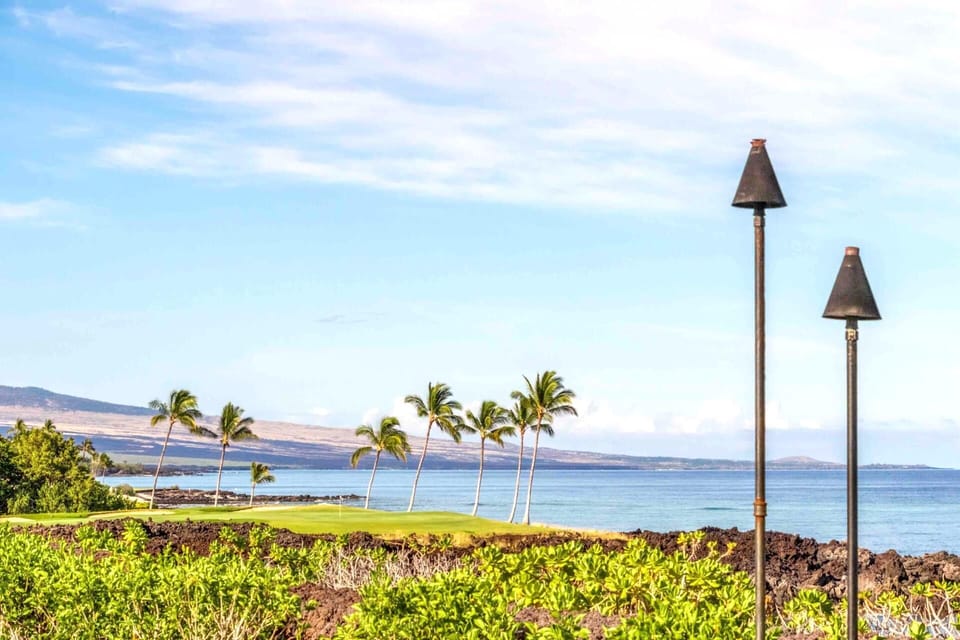 The view from Hali‘i Kai offers a symphony of nature—palm trees swaying, waves rolling in, and the horizon dancing in the distance.