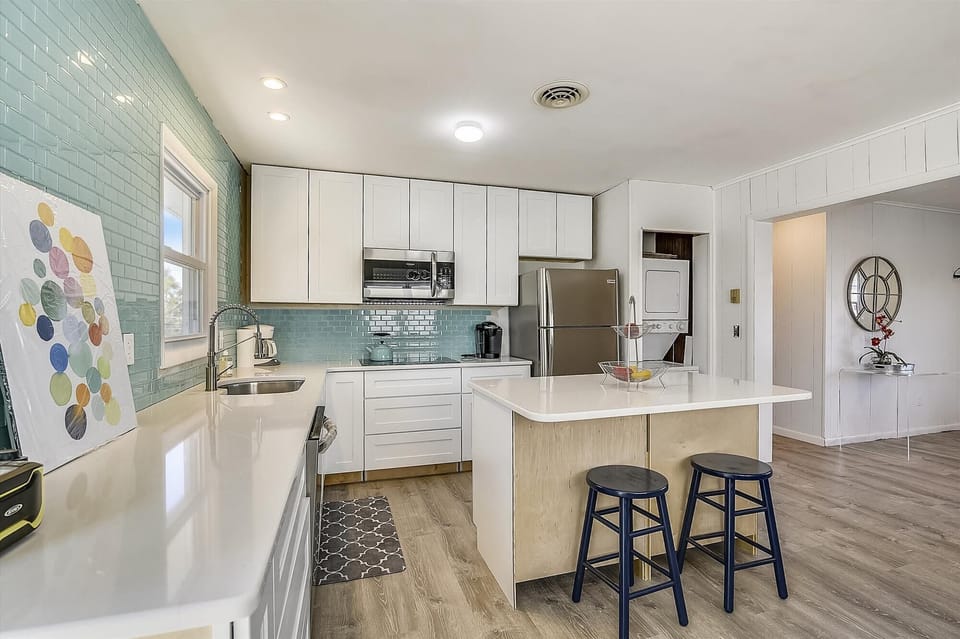 Step into your fully-equipped kitchen with stylish turquoise tile backsplash, modern appliances, and a breakfast bar—perfect for preparing meals and gathering together over morning coffee.