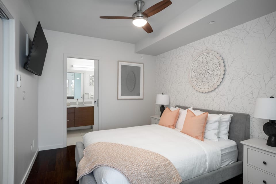 A broad view of the bedroom layout, highlighting the modern ceiling fan to keep you cool and comfortable throughout your stay.
