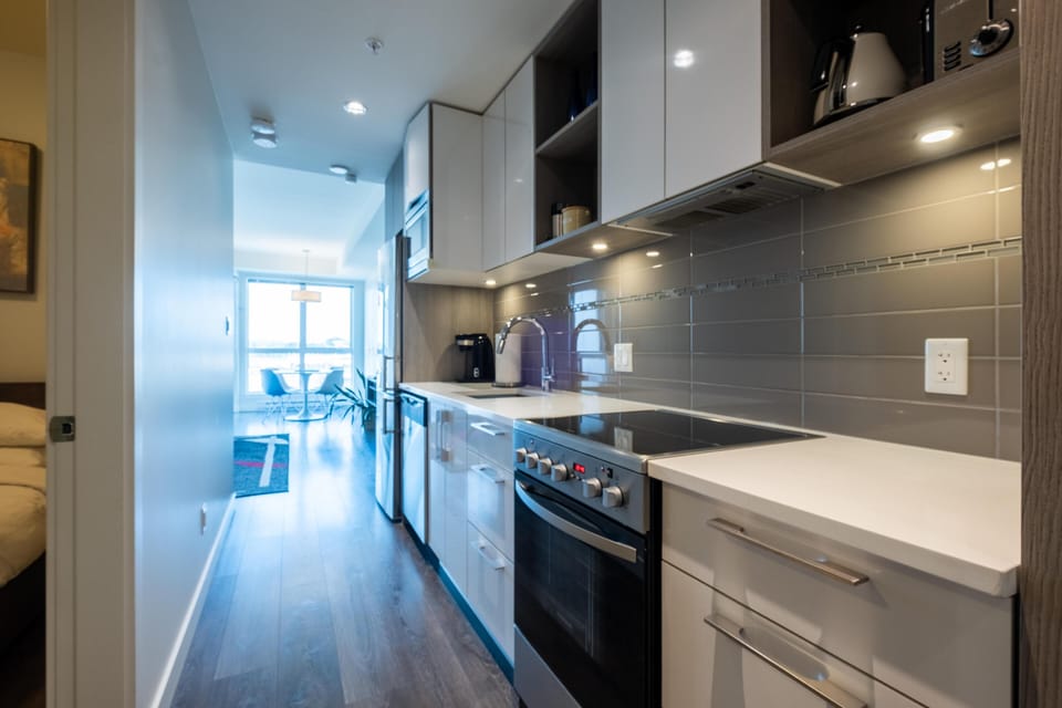 A fully equipped chef's kitchen featuring modern cabinetry, premium stainless steel appliances, a tiled backsplash, and ample counter space.