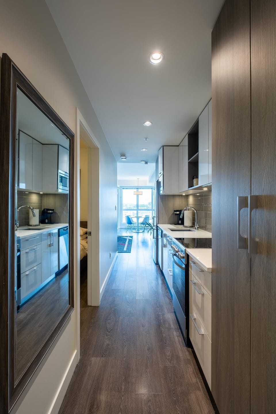 A long look down the functional kitchen and hallway corridor, showcasing the sleek, clean lines of the entryway layout.