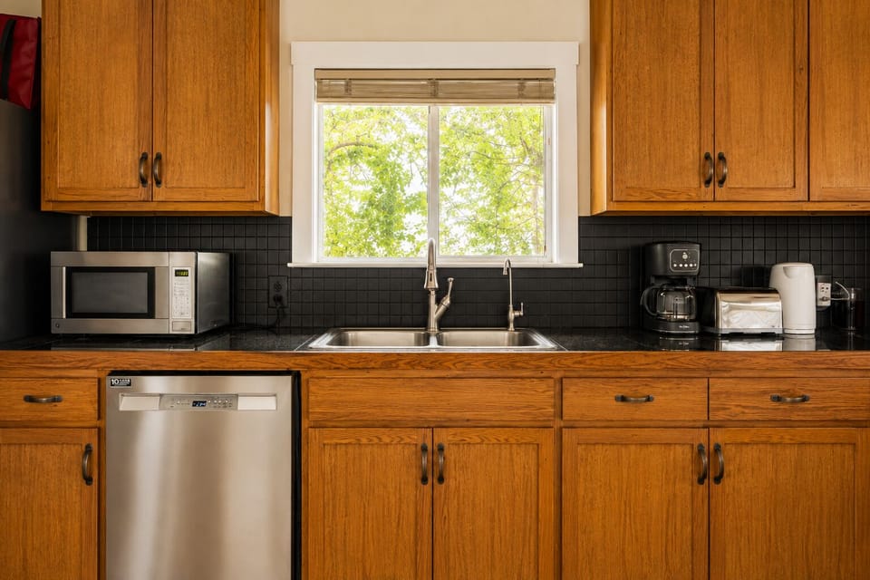 Bright kitchen with leafy window views, double sink, and handy guest appliances