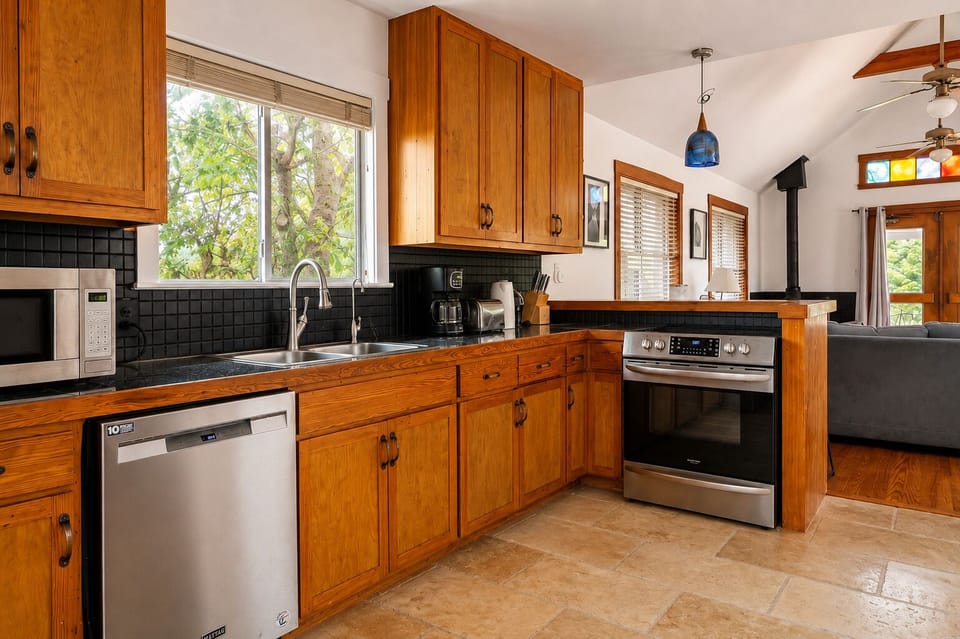 Bright open kitchen with warm wood cabinetry and leafy window views