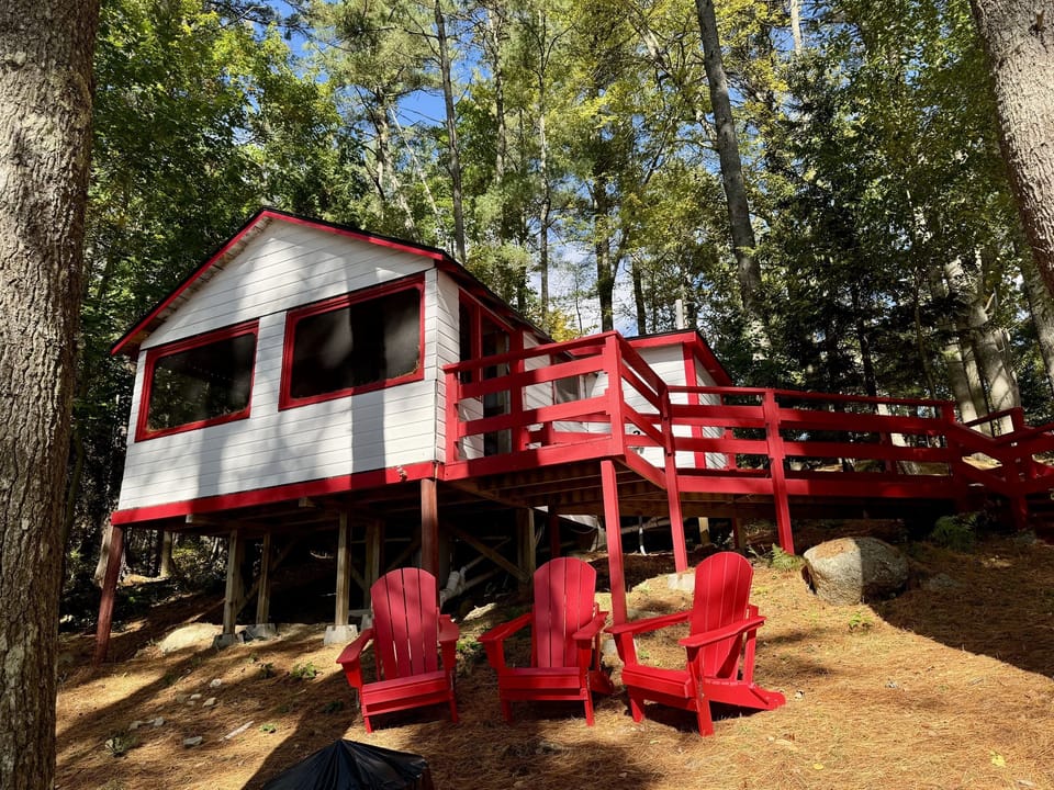 Nestled deep in the woods, this charming white and red cabin offers rustic tranquility with a touch of classic charm