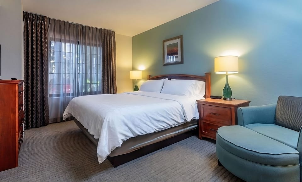 Unwind in a serene king bed with soft lamplight.