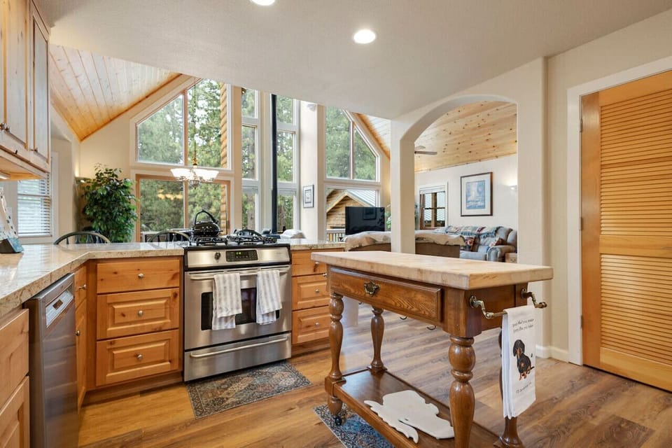 Cook with a view 🍳 Surrounded by warm wood finishes and natural light, this well-equipped kitchen makes mealtime a joy—especially with those soaring windows and forest views!