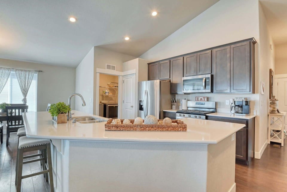 Farmhouse Chic Kitchen with Modern Elegance Experience a stylish farmhouse-chic kitchen with modern finishes, high vaulted ceiling, and stainless steel appliances. Perfect for preparing gourmet meals, this open-concept kitchen features a large island