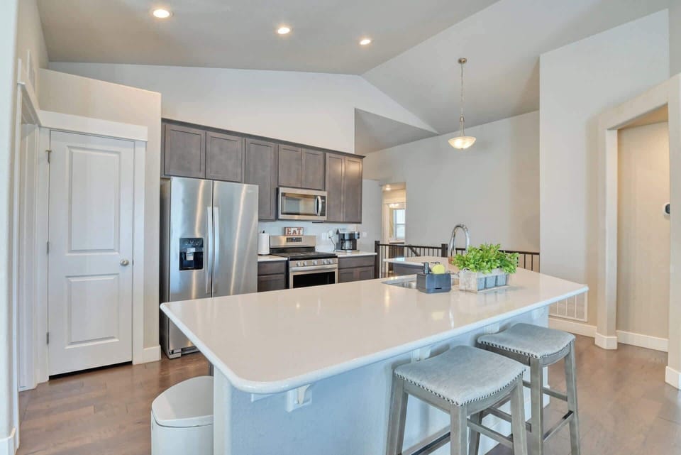 Cook and entertain in style in this spacious open-plan kitchen with sleek breakfast bar. With plenty of natural light, beautiful hardwood floors, and a welcoming atmosphere, this kitchen is perfect for hosting friends and family during your stay.