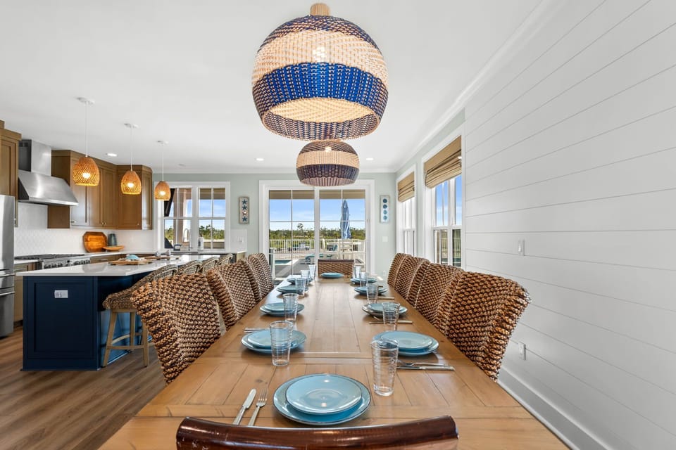 Gather around this inviting dining table where coastal charm meets comfort. The handwoven light fixtures and wicker chairs create a relaxed atmosphere perfect for memorable meals with your loved ones.