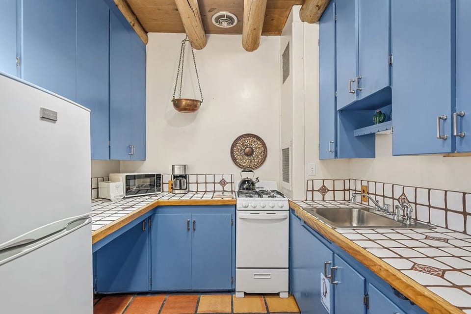 Your charming kitchen features vigas, cheerful blue cabinets, and tiled counters.