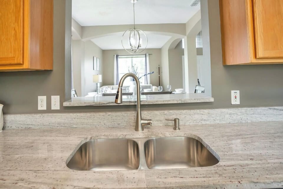 Modern kitchen sink with granite countertops and a view into the dining area.
