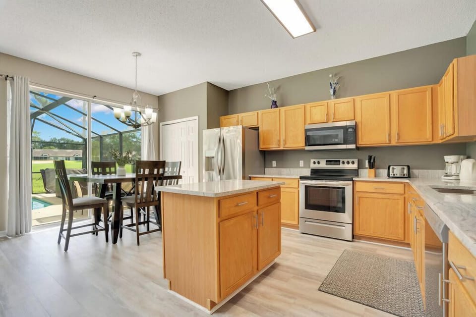 Modern kitchen with stainless steel appliances and a dining area overlooking a screened pool.