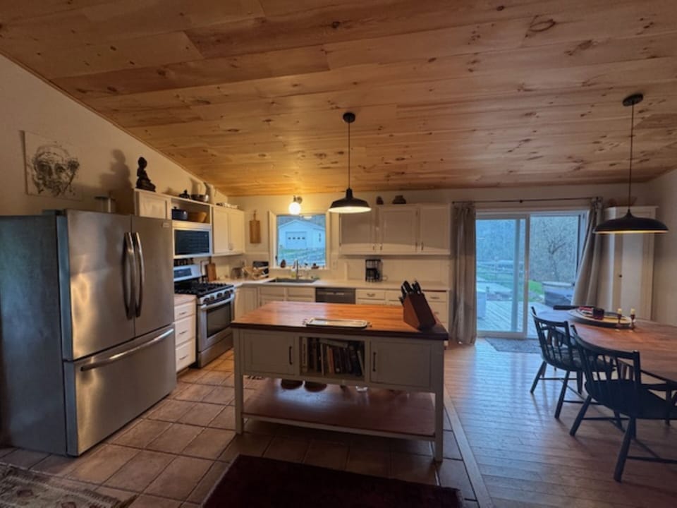 Kitchen w large island +DR, W sliding glass doors to deck pool and Hot tub