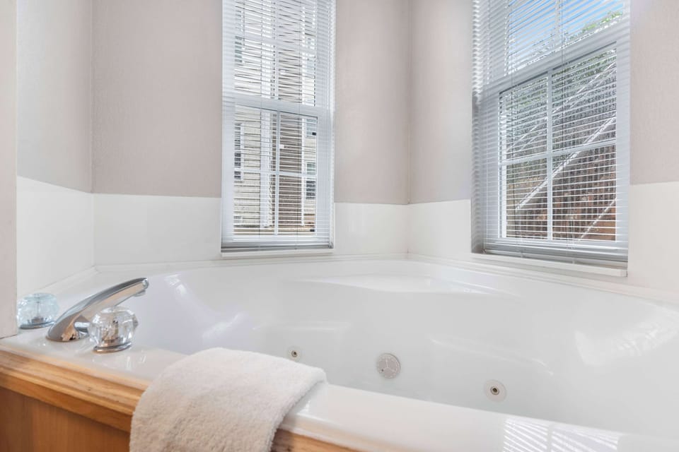 This luxe ensuite features a double vanity, glass shower, & soaking tub