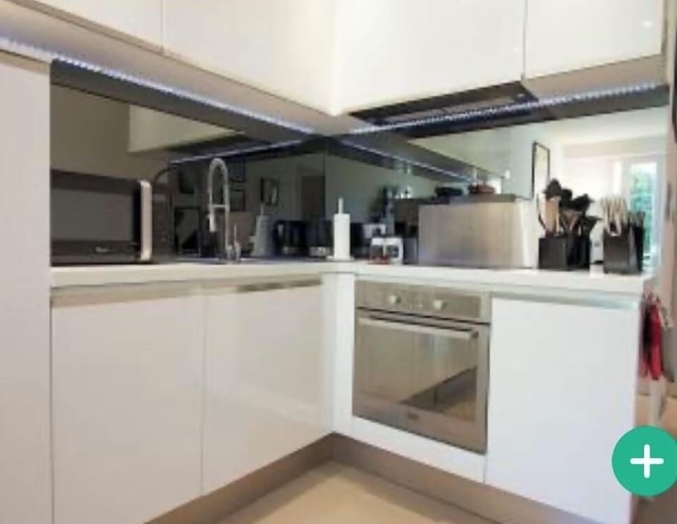 Modern kitchen with microwave, oven, glass hob and large refrigerator.