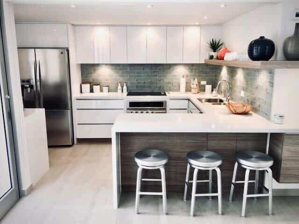 White melamine countertops and cupboards
Three-bar stool service countertop
Flat-top stove
Conventional oven
Double-door refrigerator with ice maker
Dishwasher
Double sink
Wine Cooler