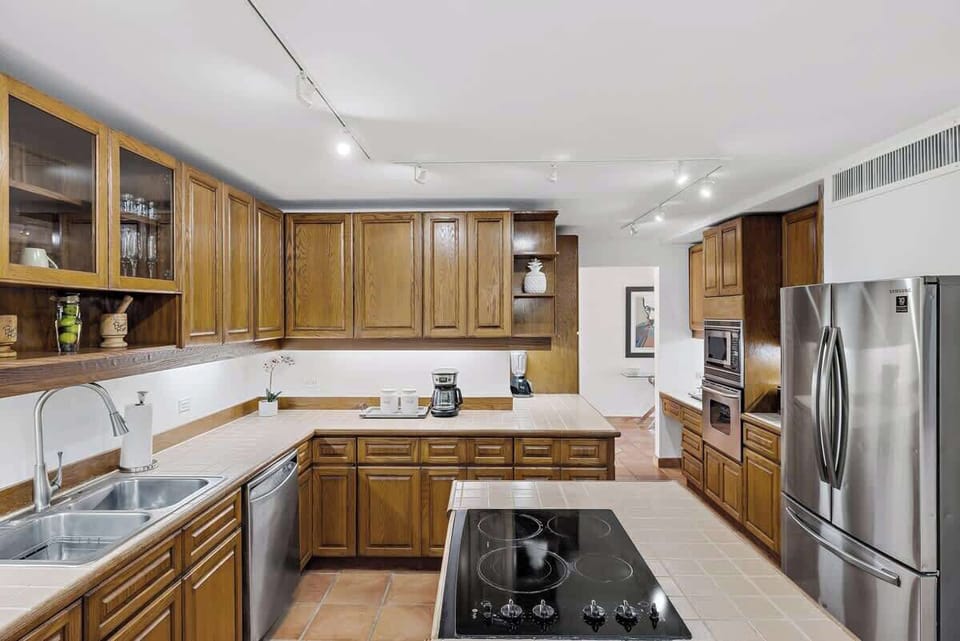 Kitchen is adjacent to a six-seater dining area nestled in a bright bay-window cove
Fully equipped
Wood-finished cabinets and tiled countertops
Flat-top cooking range embedded in a central island
