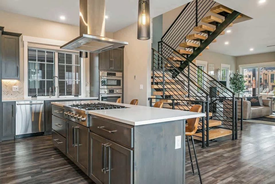 - Chef’s island anchors the open plan design with built in gas burners and sleek cabinetry
- Floating stairs and black railing add a bold, contemporary edge
- Perfect for prepping meals while staying connected to the whole group